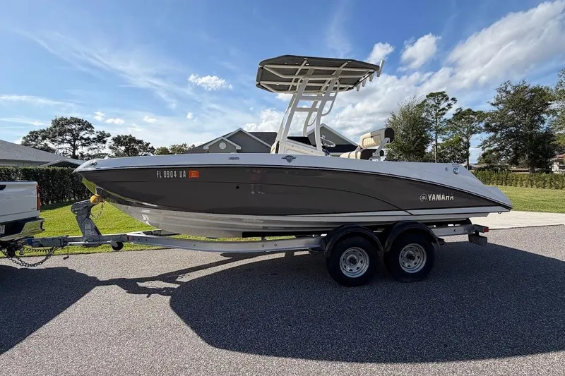 Slide: The Image of 2022 Yamaha Boats 210 FSH Sport on trailer, parked outdoors under blue sky. - 2