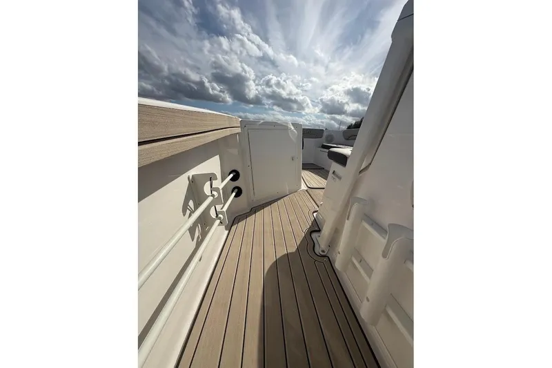 Slide: The Image of 2022 Yamaha Boats 210 FSH Sport deck with rod holders under a cloudy sky. - 8