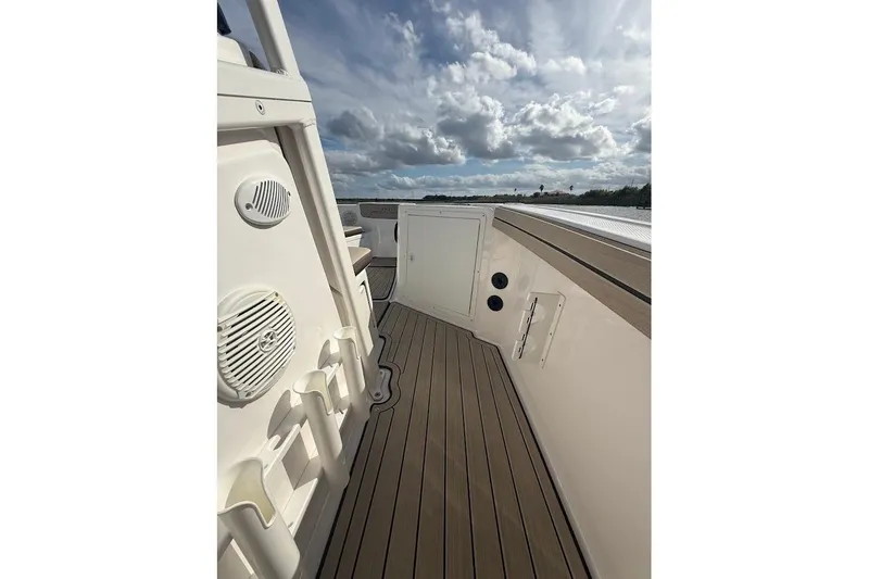 Slide: The Image of 2022 Yamaha Boats 210 FSH Sport deck with rod holders and speakers under a cloudy sky. - 9