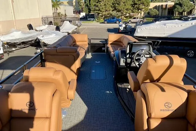Slide: The Image of Luxurious 2026 Regency 250DL pontoon boat with tan leather seating in a sunny marina. - 14