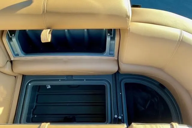 Slide: The Image of 2026 Regency 250DL boat storage compartments with tan upholstery and open hatches. - 27