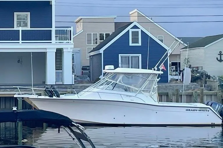 Slide: The Image of 2004 Grady-White Express 330 boat docked near blue waterfront houses. - 2