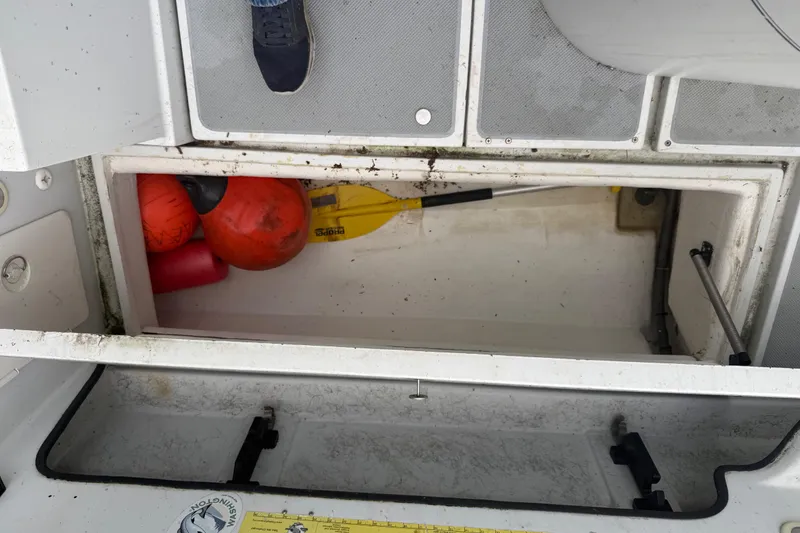 Slide: The Image of Open storage compartment on 1998 Davis Rock Harbor 25 boat with buoys and paddle. - 26