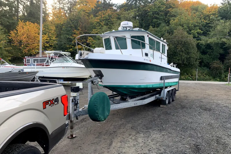 Slide: The Image of 1998 Davis Rock Harbor 25 boat on trailer, surrounded by autumn trees. - 3