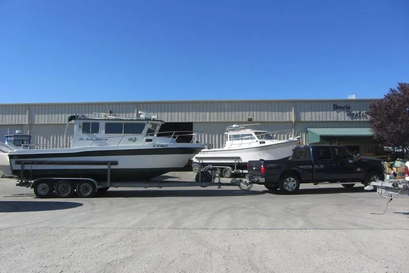 Slide: The Image of 1998 Davis Rock Harbor 25 boat on trailer, parked outside a warehouse under clear blue sky. - 5