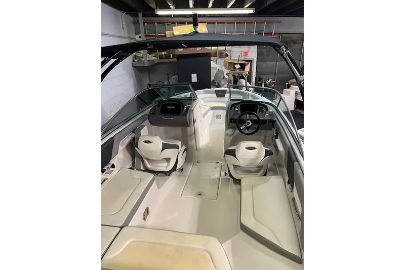 Slide: The Image of 2020 Chaparral 23 SSi boat interior with seating and steering wheel in a garage. - 5