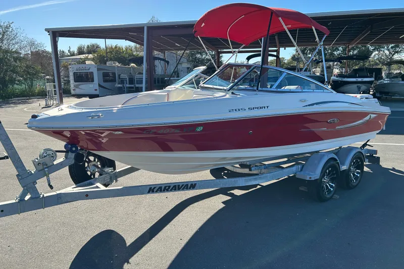 Slide: The Image of 2010 Sea Ray 205 Sport boat on Karavan trailer, red and white design, parked outdoors. - 5