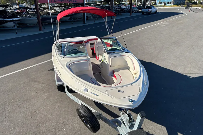 Slide: The Image of 2010 Sea Ray 205 Sport boat with red canopy on trailer in parking lot. - 6