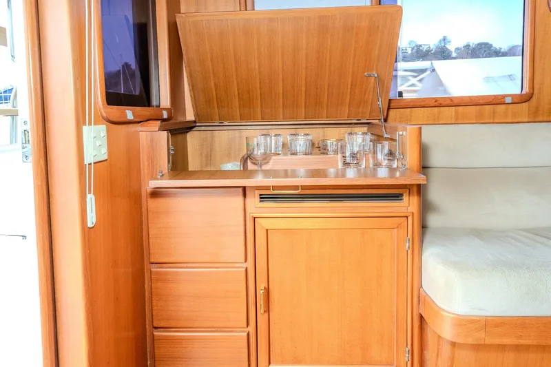 Slide: The Image of Interior of 2001 Fleming 55 Pilothouse with wooden cabinetry and glassware storage. - 13