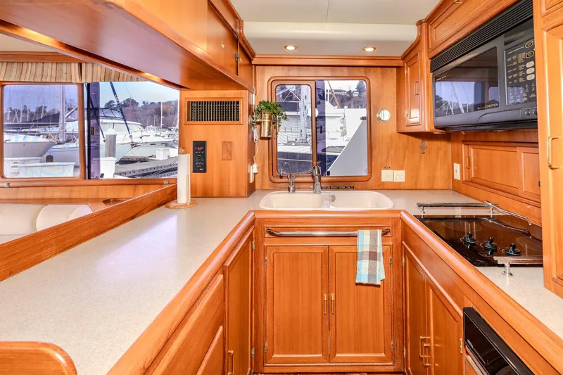 Slide: The Image of Luxurious 2001 Fleming 55 Pilothouse yacht kitchen with wood cabinetry and marina view. - 18