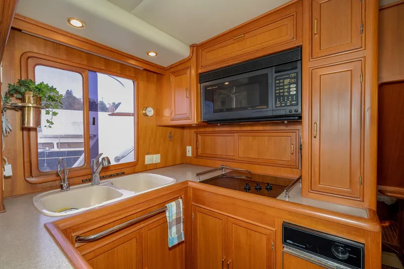 Slide: The Image of 2001 Fleming 55 Pilothouse kitchen with wood cabinetry, dual sink, and built-in microwave. - 19
