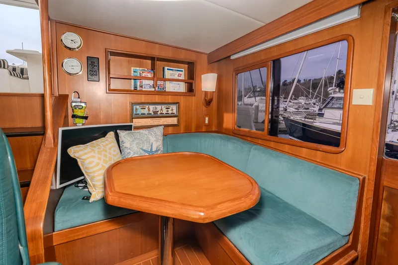 Slide: The Image of Cozy interior of 2001 Fleming 55 Pilothouse yacht with wooden table and teal seating. - 27