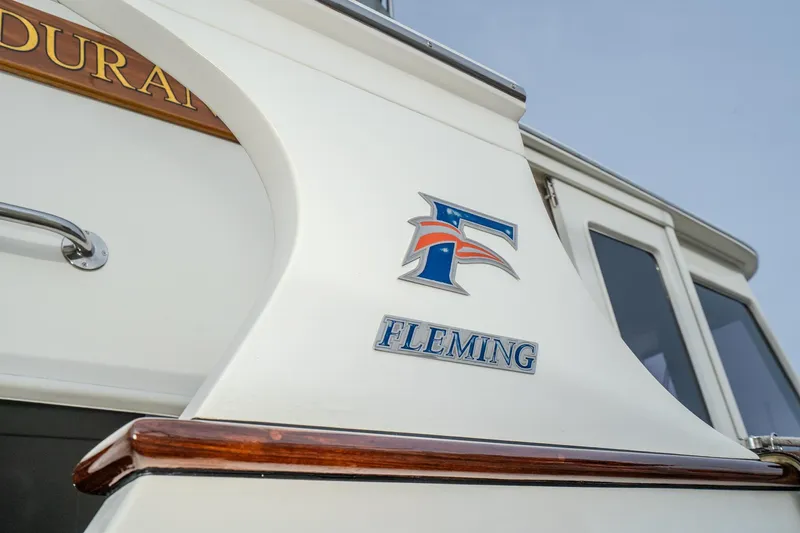 Slide: The Image of 2001 Fleming 55 Pilothouse yacht with logo and wooden trim detail. - 3