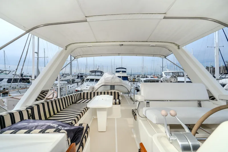 Slide: The Image of 2001 Fleming 55 Pilothouse yacht interior with striped seating and marina view. - 35