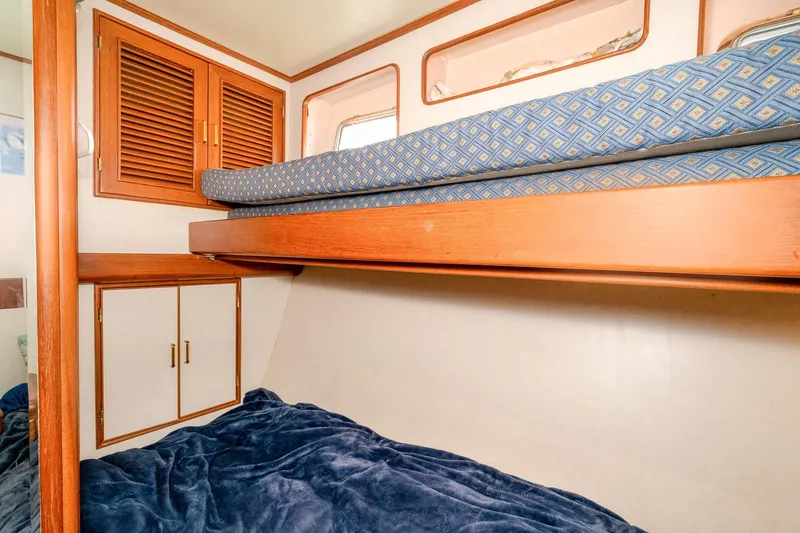 Slide: The Image of Bunk beds in 2001 Fleming 55 Pilothouse cabin with wooden storage and blue bedding. - 57