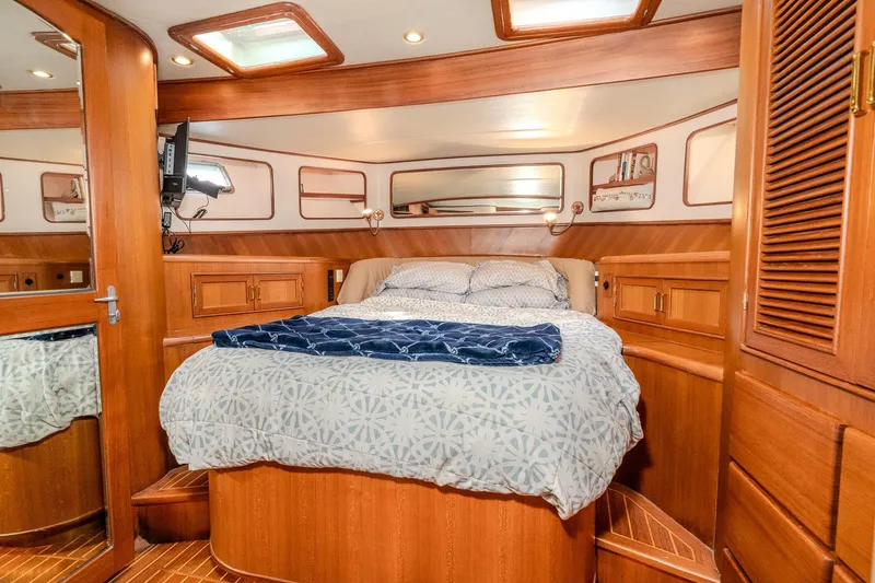 Slide: The Image of Luxurious 2001 Fleming 55 Pilothouse yacht bedroom with wood paneling and cozy bedding. - 64