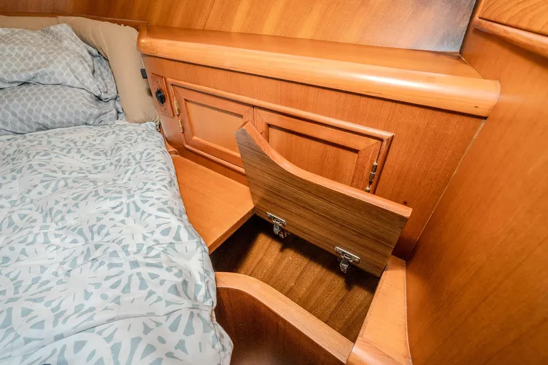Slide: The Image of Wooden storage compartment in 2001 Fleming 55 Pilothouse bedroom, next to patterned bedding. - 67