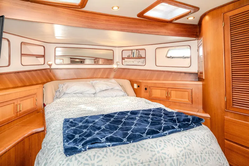 Slide: The Image of Luxurious 2001 Fleming 55 Pilothouse yacht bedroom with wood accents and cozy bedding. - 68