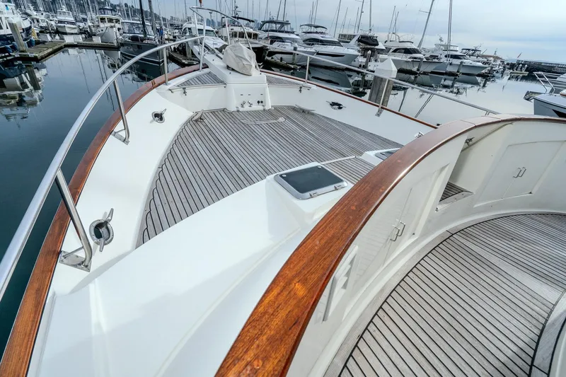 Slide: The Image of 2001 Fleming 55 Pilothouse yacht deck with wooden railings in marina setting. - 77
