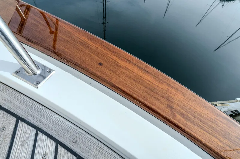 Slide: The Image of Polished wood railing on 2001 Fleming 55 Pilothouse yacht, reflecting in calm water. - 80