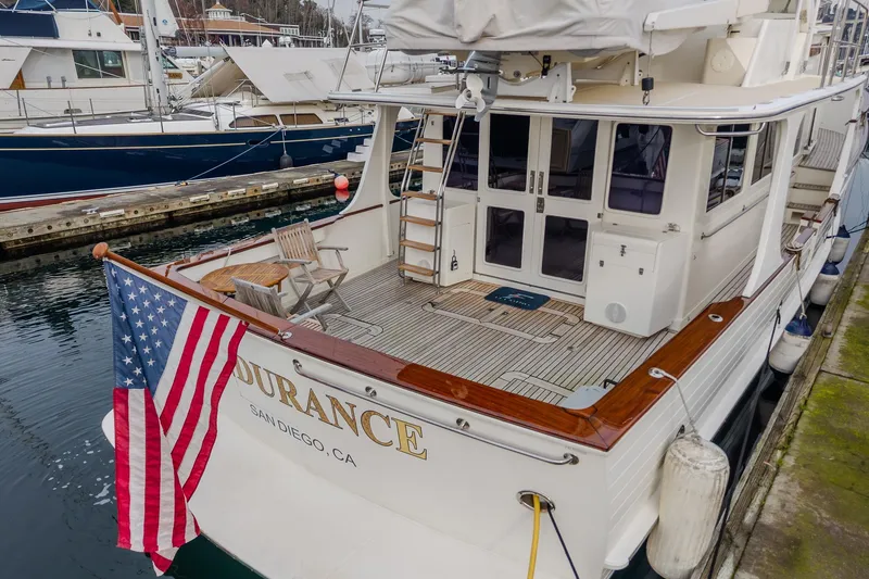 Slide: The Image of 2001 Fleming 55 Pilothouse yacht docked, featuring American flag and wooden deck chairs. - 9