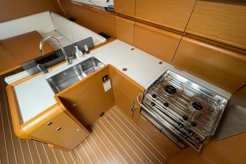 Slide: The Image of 2014 Jeanneau Sun Odyssey 439 yacht kitchen with stove, sink, and wooden cabinetry. - 21