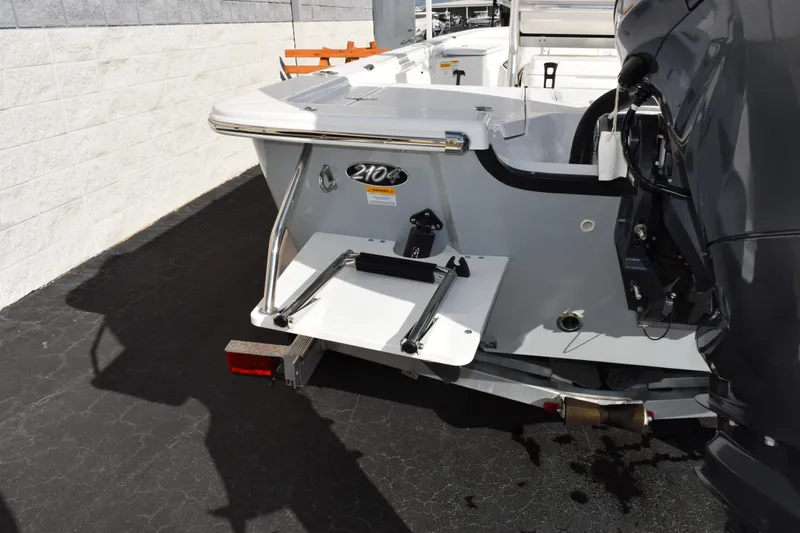 Slide: The Image of 2026 Frontier 2104 boat with motor and swim platform, parked on pavement. - 7