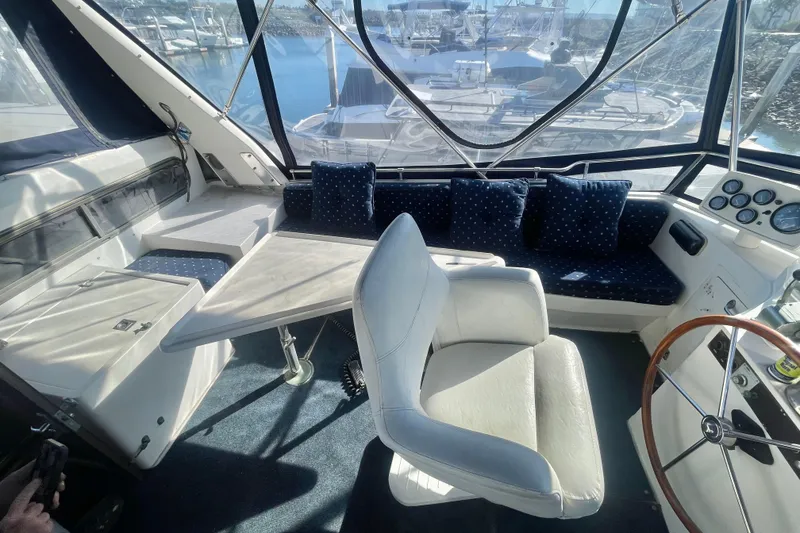 Slide: The Image of 1990 Spindrift Cockpit Motoryacht interior with seating, table, and helm in marina setting. - 19