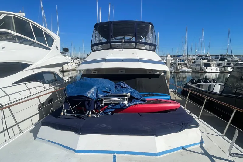 Slide: The Image of 1990 Spindrift Cockpit Motoryacht docked, featuring covered equipment and paddleboards on deck. - 3