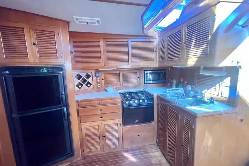 Slide: The Image of 1990 Spindrift Cockpit Motoryacht kitchen with wooden cabinets, stove, and sink. - 43