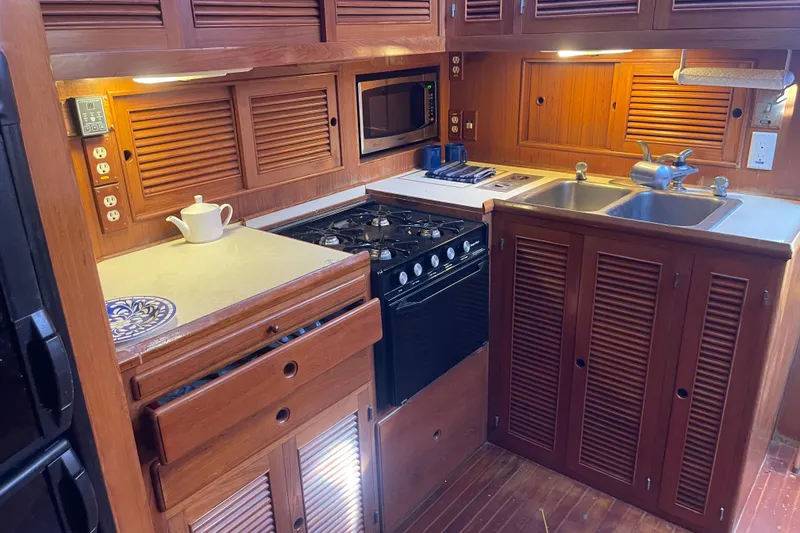 Slide: The Image of 1990 Spindrift COCKPIT MOTORYACHT kitchen with wooden cabinets, stove, and double sink. - 45
