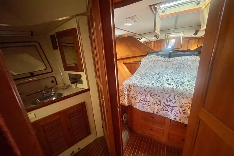 Slide: The Image of 1990 Spindrift Cockpit Motoryacht interior with bed, wooden cabinetry, and compact sink area. - 49