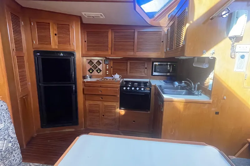 Slide: The Image of 1990 Spindrift Cockpit Motoryacht kitchen with wood cabinetry, stove, sink, and microwave. - 55