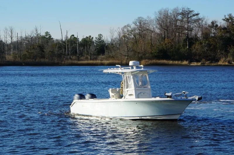 The Image of 2015 Sea Hunt Gamefish 25 boat cruising on a calm lake with wooded shoreline. - 1