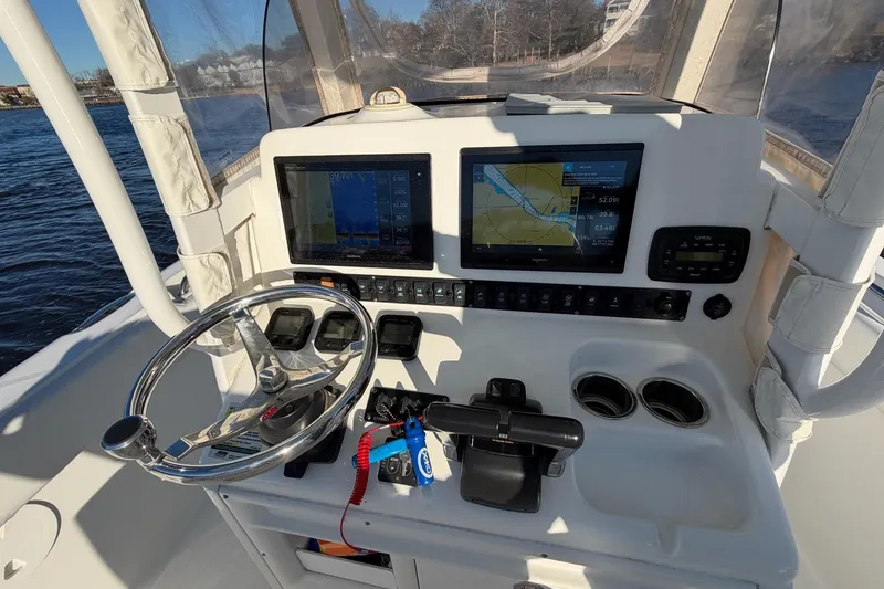 Slide: The Image of 2015 Sea Hunt Gamefish 25 helm with navigation screens and steering wheel on open water. - 10
