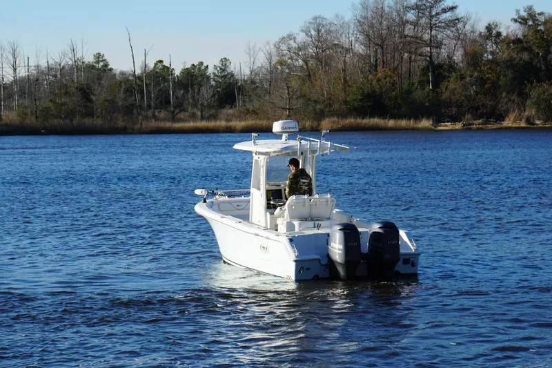 Slide: The Image of 2015 Sea Hunt Gamefish 25 boat cruising on a calm lake with wooded shoreline. - 4