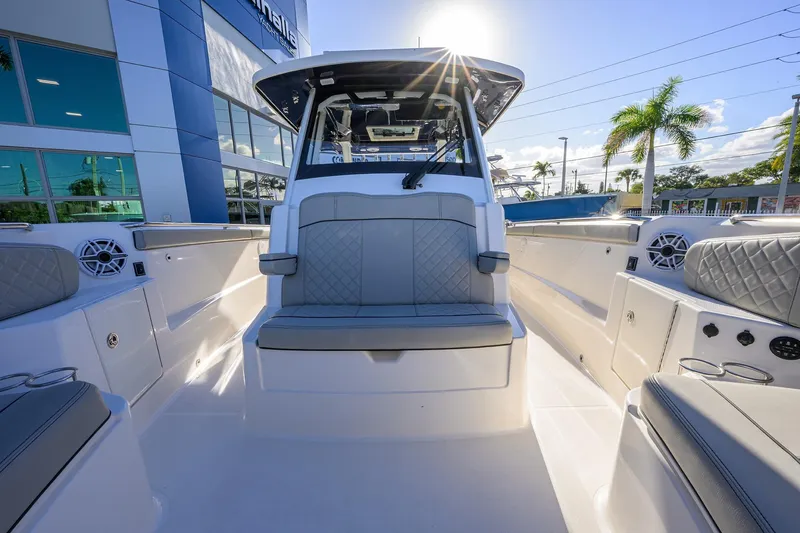 Slide: The Image of 2023 Pursuit S 328 Sport boat interior with seating, docked near a modern building. - 25