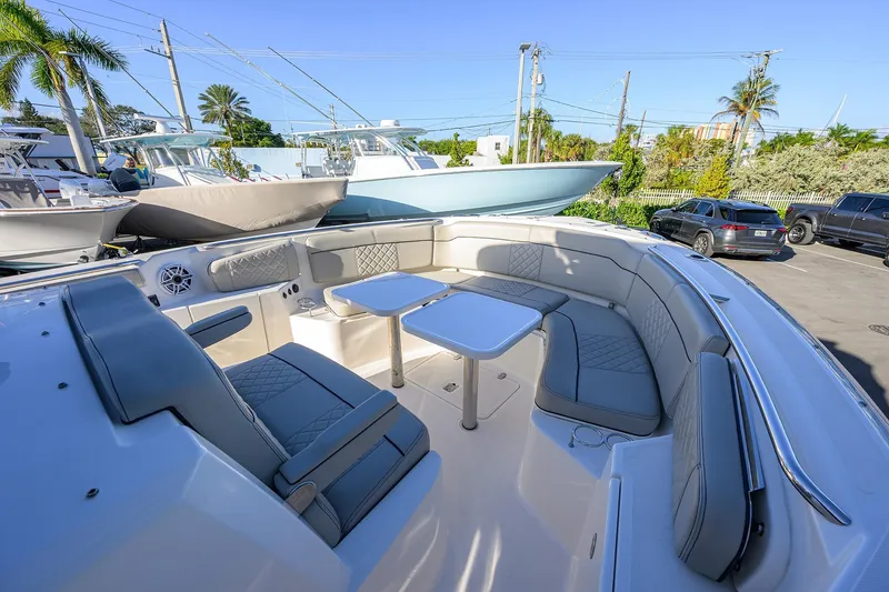 Slide: The Image of 2023 Pursuit S 328 Sport boat with luxurious seating and table in a marina setting. - 30