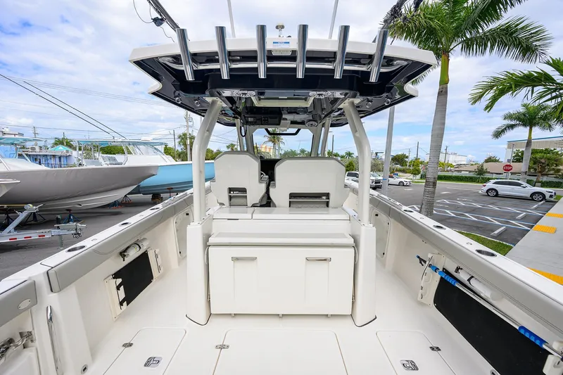 Slide: The Image of 2023 Pursuit S 328 Sport boat interior with seating and storage, docked near palm trees. - 40