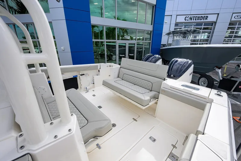 Slide: The Image of 2023 Pursuit S 328 Sport boat interior with seating and dual engines at a dealership. - 42