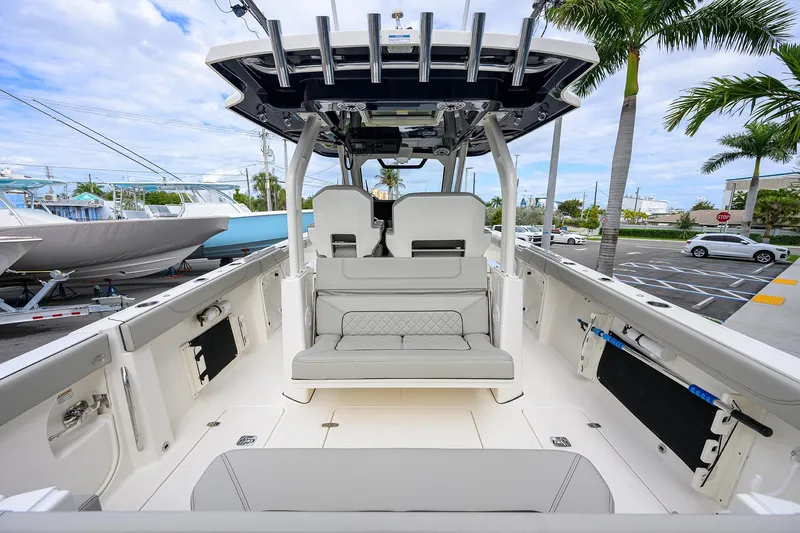 Slide: The Image of 2023 Pursuit S 328 Sport boat interior with seating, rod holders, and palm trees in the background. - 49