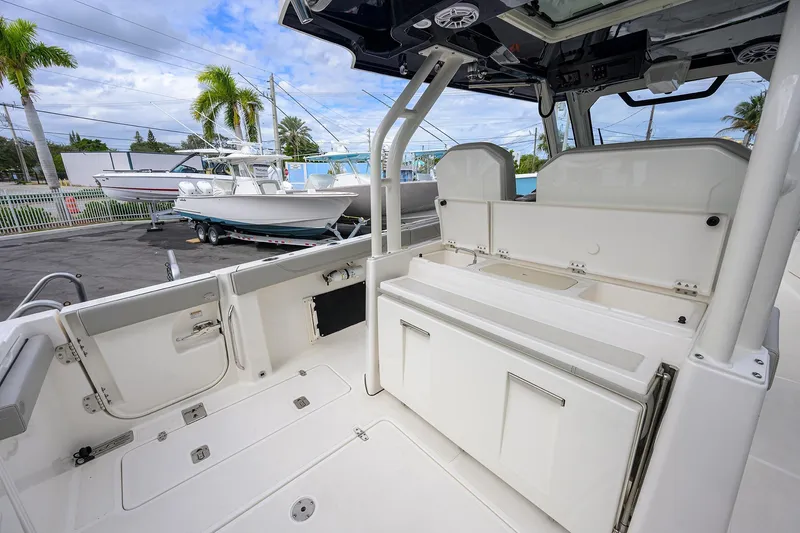 Slide: The Image of 2023 Pursuit S 328 Sport boat interior with seating and storage, docked outdoors. - 51