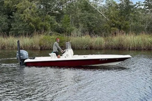 Slide: The Image of 2006 ShearWater Z2200 boat cruising on a calm river with lush greenery. - 2
