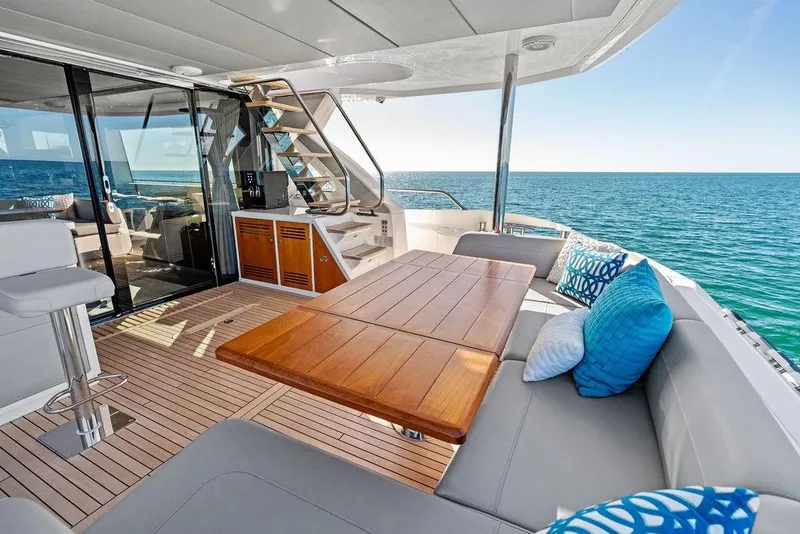 Slide: The Image of Luxurious 2019 Sunseeker 76 Yacht deck with ocean view, featuring elegant seating and wooden table. - 59