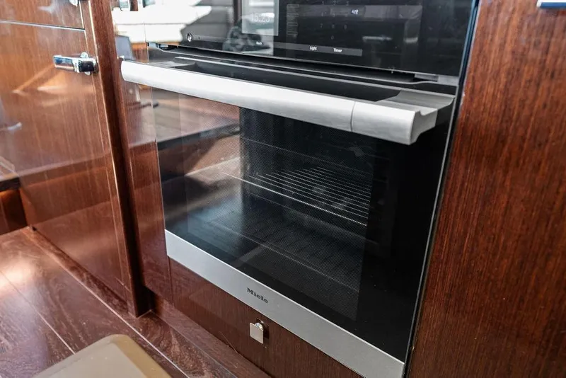 Slide: The Image of Modern kitchen oven in 2019 Sunseeker 76 Yacht, featuring sleek wood paneling. - 62