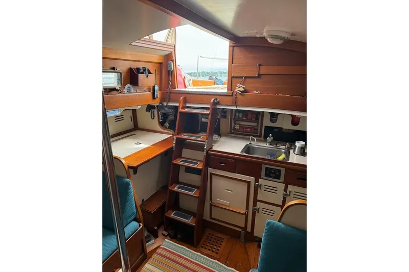 Slide: The Image of Interior of 1962 Ted Hood Little Harbor 40 Yawl, featuring wooden cabinetry and compact kitchen. - 4