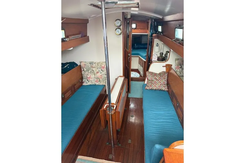 Slide: The Image of Interior of 1962 Ted Hood Little Harbor 40 Yawl, featuring cozy wooden furnishings and blue cushions. - 6