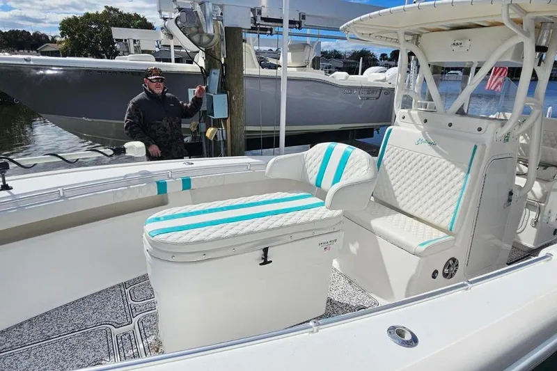 Slide: The Image of 2002 Yellowfin 31 Center Console boat with white and teal seating, docked by the water. - 12
