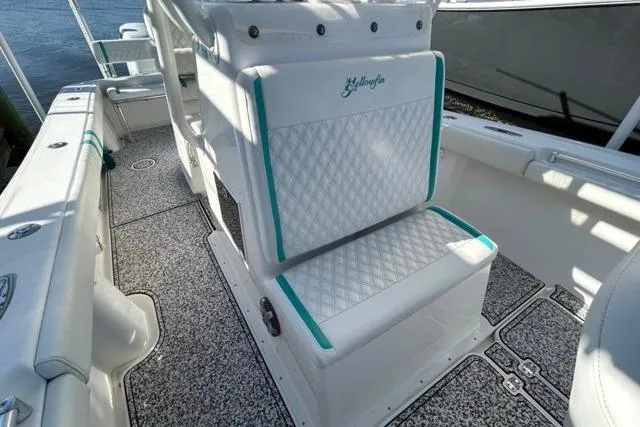 Slide: The Image of 2002 Yellowfin 31 Center Console boat interior with white and teal seating, textured flooring. - 27