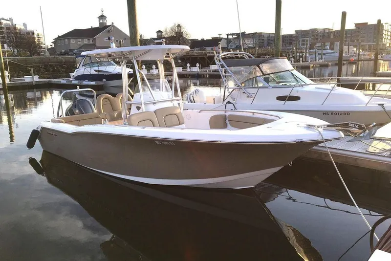 The Image of 2015 Tidewater 232 LXF boat docked at a marina, reflecting on calm water. - 0